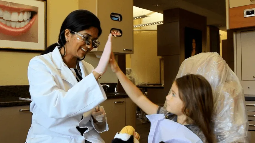 About Bay Area Kids Dentistry: Dr. Subramanian high-fiving a child patient in the dentist chair, demonstrating compassionate care in San Jose